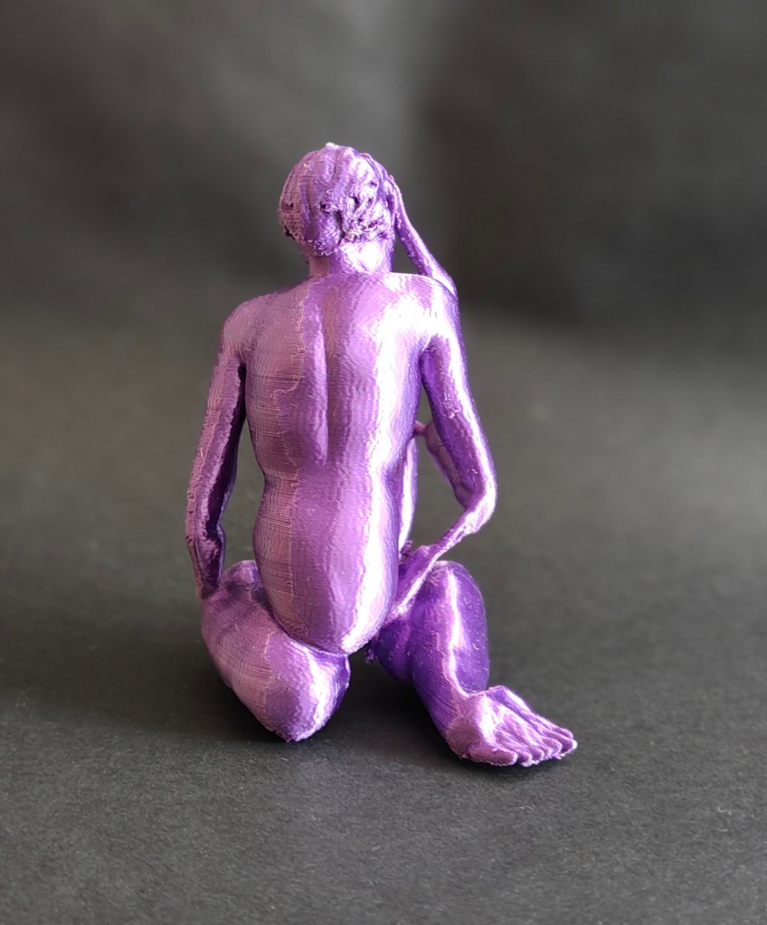 A purple 3D-printed sculpture of a seated figure, viewed from the back, with a serene pose and a hand resting on the head.